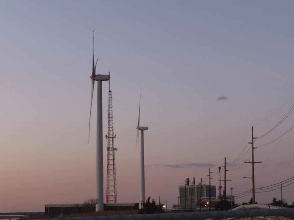 The sun sets behind a land-based wind farm in Atlantic City, N.J. on Feb. 10, 2022. On Monday, March 6, 2023, New Jersey utility regulators issued a solicitation for additional offshore wind energy projects beyond the three already approved by the state. (AP Photo/Wayne Parry)