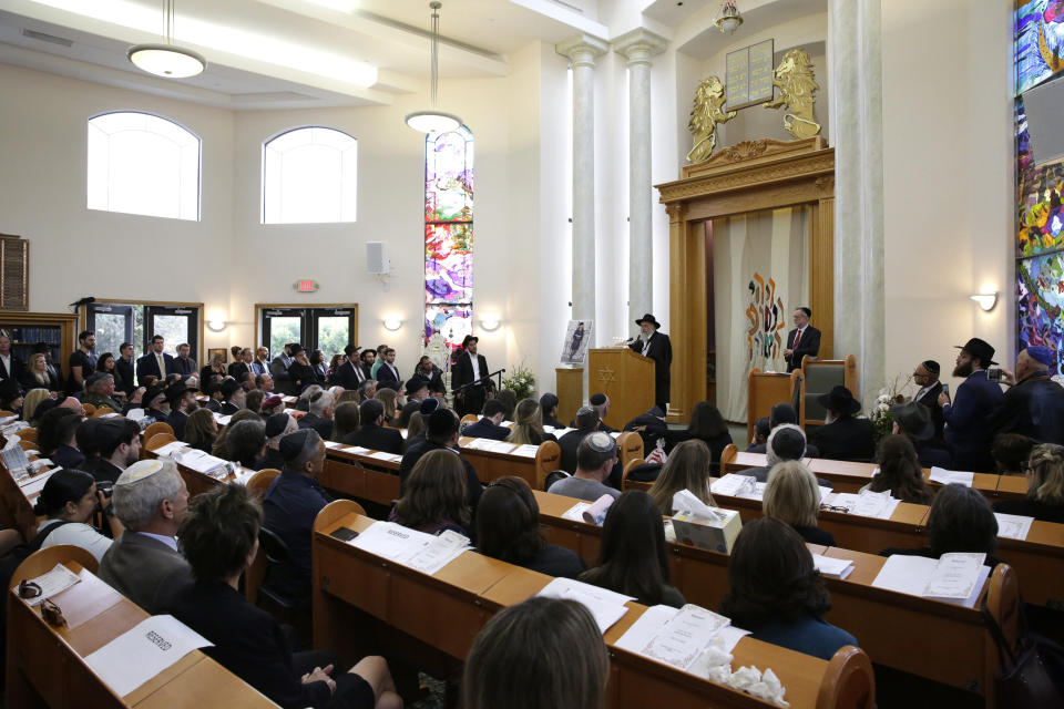 FILE - In this April 29, 2019 file photo, Yisroel Goldstein, at podium, Rabbi of Chabad of Poway, speaks during a memorial service for Lori Kaye, who was Kaye was was killed Saturday when a gunman opened fire inside the ysnagogue. The gunman who attacked the synagogue last week fired his semi-automatic rifle at Passover worshippers after walking through the front entrance that synagogue leaders identified last year as needing improved security. The synagogue applied for a federal grant to better protect that area. The money, $150,000, was approved in September but only arrived in late March. "Obviously we did not have a chance to start using the funds yet," Rabbi Scimcha Backman told The Associated Press. (AP Photo/Gregory Bull, File)
