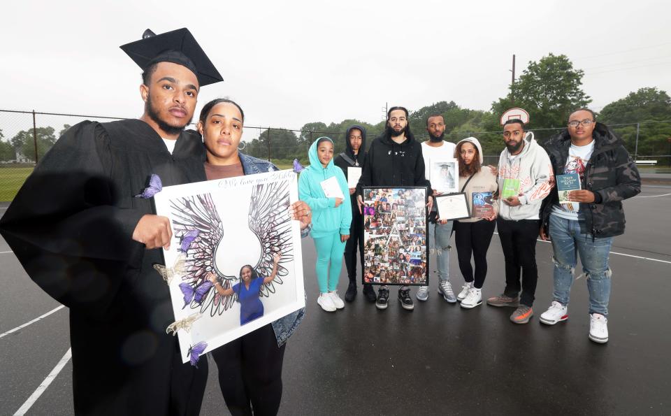 Family members from left, Kayden Lopes, Liseth Carey,  Kalya Lopes, Ricardo Andrade, Daniel Andrade, Jonathan Rodrigues, Jarah Rodrigues, John Rodrigues and Kayson Lopes, hold photos and other keepsakes of the late Ashley Cardoso at East Middle School in Brockton on Saturday, June 3, 2023.