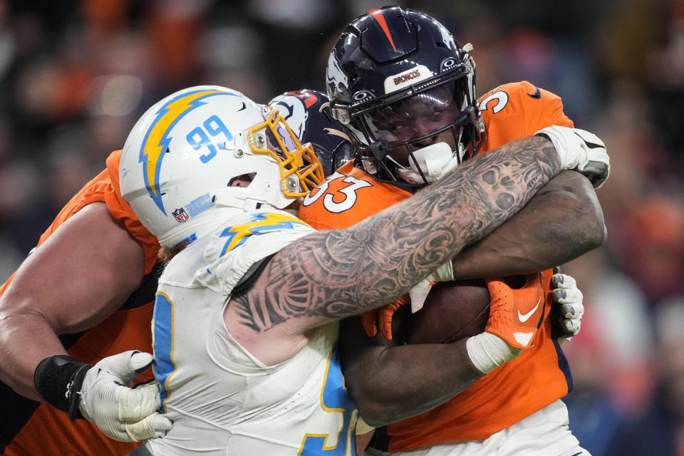 Los Angeles Chargers defensive tackle Scott Matlock (99) tackles Denver Broncos running back Javonte Williams (33) during the second half of an NFL football game, Sunday, Dec. 31, 2023, in Denver. (AP Photo/David Zalubowski)