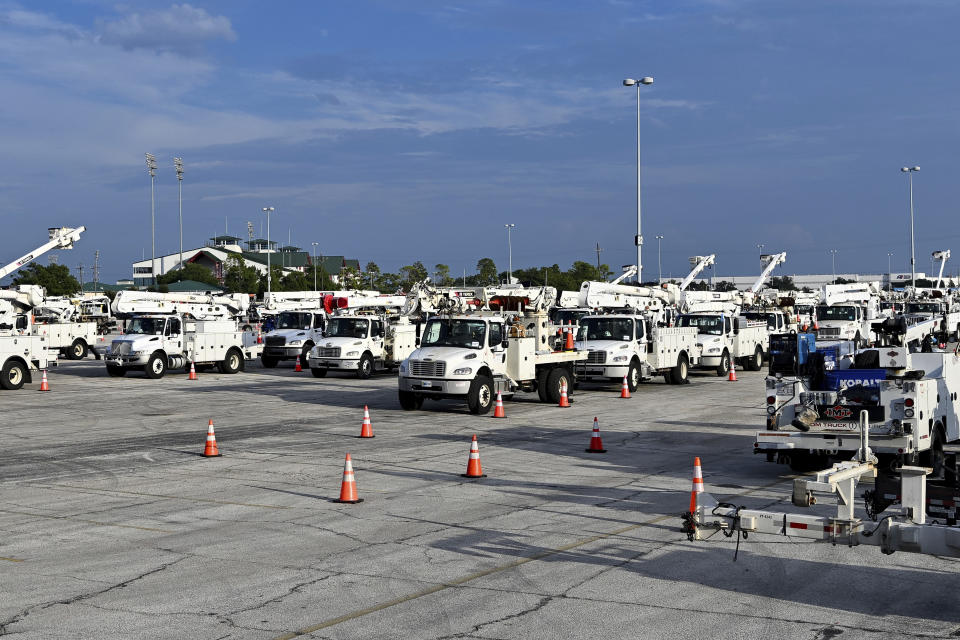 Utility trucks sit parked at a CenterPoint Energy staging center at the Houston Race Track in Houston, Wednesday, July 10, 2024. Millions of residents lost power after Hurricane Beryl made landfall. (AP Photo/Maria Lysaker)