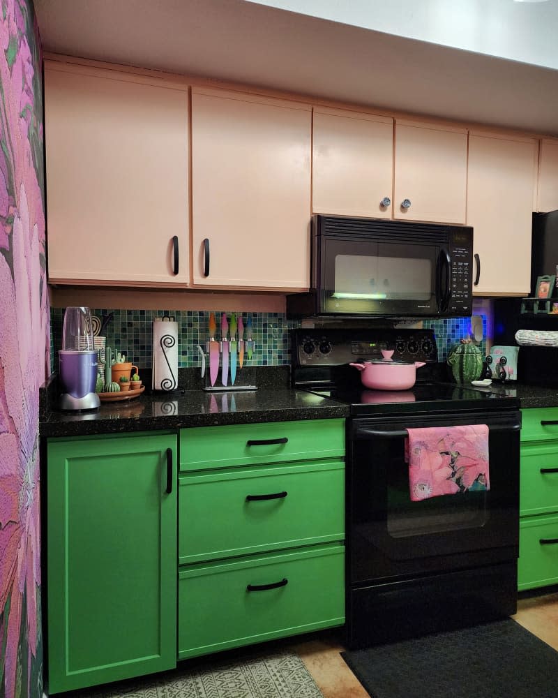 Pink upper cabinets and green lower cabinets in colorful kitchen.