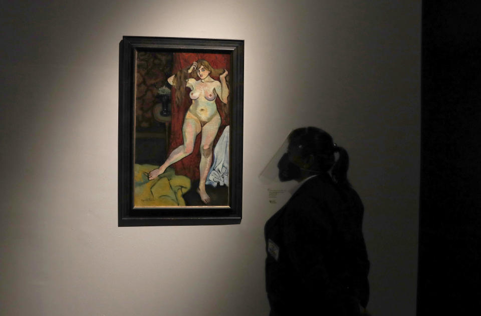 A museum guard stands next to a painting by Suzanne Valadon during the "El Paris de Modigliani y sus Contemporáneos" or The Paris of Modigliani and his contemporaries exhibit at the Palacio de Bellas Artes in Mexico City, Monday, Sept. 7, 2020. The museum opens its doors for the first time since the new coronavirus pandemic lockdown with the exhibit of the early 20th century Italian Jewish painter and sculptor Amedeo Modigliani and his fellow artists. (AP Photo/Marco Ugarte)