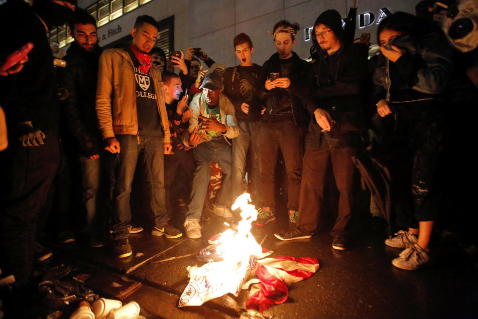 Demonstrators burn the U.S. flag outside Trump Tower during a march against President-elect Donald Trump in Manhattan, New York, U.S. November 9, 2016. REUTERS/Andrew Kelly   