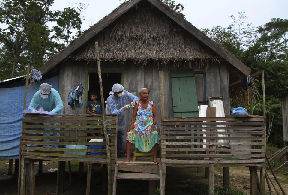 Maria Castro de Lima, 72, receives a dose of the Oxford-AstraZeneca COVID-19 vaccine from a healthcare worker, while sitting on the porch of her home in the Recanto community, along the Purus River, in the Labrea municipality, Amazonas state, Brazil, Friday, Feb. 12, 2021. (AP Photo/Edmar Barros)