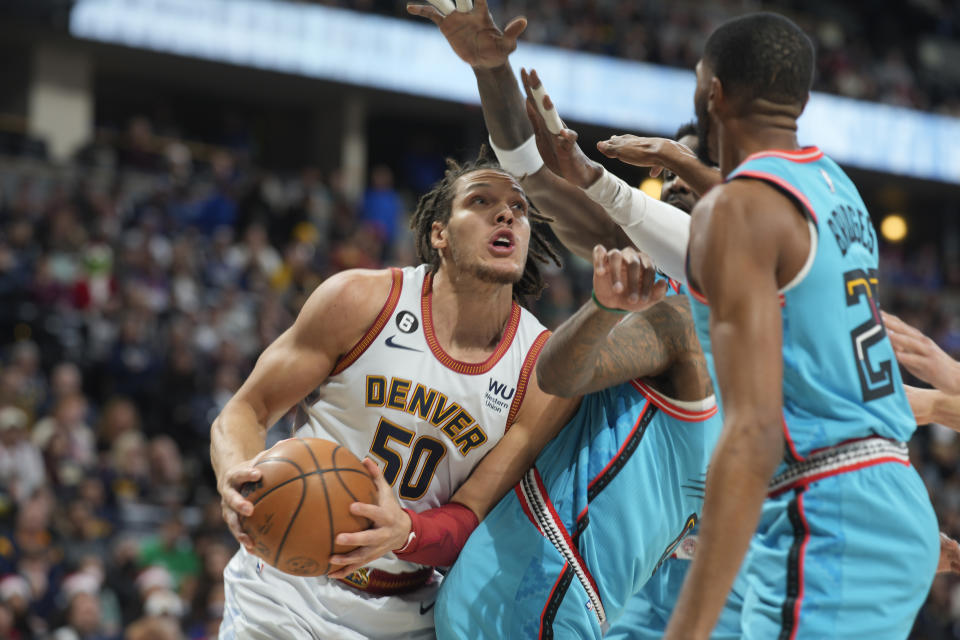 Denver Nuggets forward Aaron Gordon, left, goes up for a basket as, from right front to back, Phoenix Suns forward Mikal Bridges, guard Chris Paul and center Deandre Ayton defend in the first half of an NBA basketball game Sunday, Dec. 25, 2022, in Denver. (AP Photo/David Zalubowski)