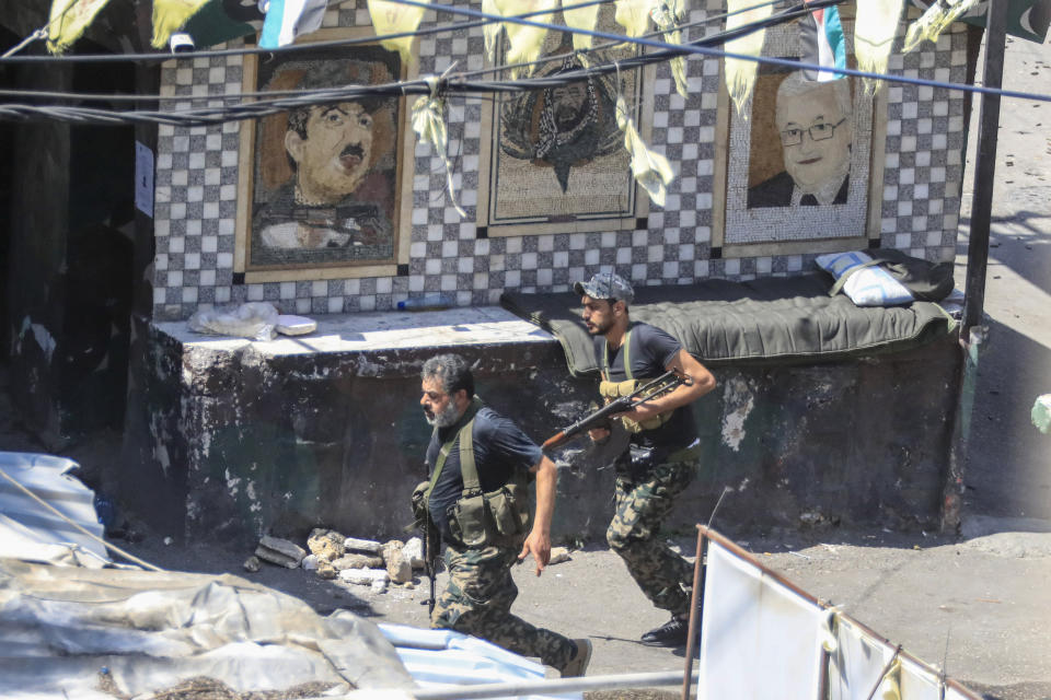 FILE - Members of the Palestinian Fatah group run to take position during a third day of clashes that erupted with Islamist factions in the Palestinian refugee camp of Ein el-Hilweh near the southern port city of Sidon, Lebanon on July 31, 2023. Two weeks after clashes between armed factions in Lebanon's largest Palestinian refugee camp ended, militants are still occupying a United Nations-run school complex, U.N. officials said Thursday Aug. 17, 2023. (AP Photo/Mohammad Zaatari, File)