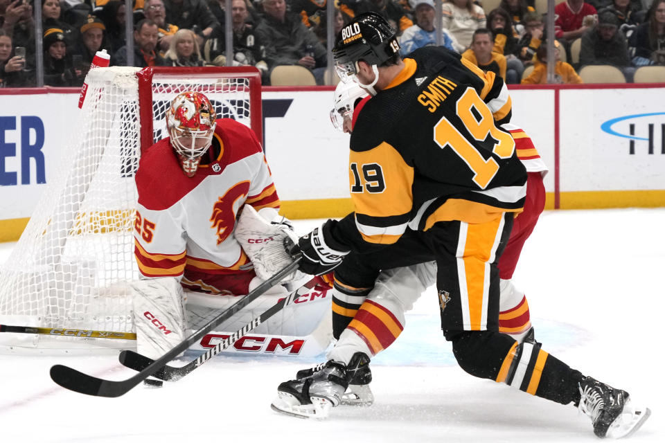 Pittsburgh Penguins' Reilly Smith (19) can't get off a shot in front of Calgary Flames goaltender Jacob Markstrom (25) with Chris Tanev defending during the second period of an NHL hockey game in Pittsburgh, Saturday, Oct. 14, 2023. (AP Photo/Gene J. Puskar)