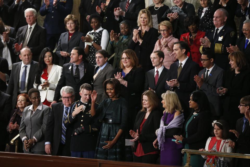 ** ADDS NAMES ** First lady Michelle Obama waves as she arrives for President Barack Obama's State of the Union address on Capitol Hill in Washington, Tuesday Jan. 28, 2014. Front row, second from left are, Sabrina Simone Jenkins, Craig, Remsburg, Sgt. 1st Class Cory Remsburg, first lady Michelle Obama, Misty DeMars, Jill Biden, Kathy Hollowell-Makle, Aliana Arzola-Pinero and Joey Hudy. Second row, third from left are, Jeff Bauman, Carlos Arredondo, Amanda Shelly, Nick Chute, John Soranno, Estiven Rodriguez, and General Motors CEO Mary Barra. Third row, second from right are, Antoinette Tuff, and Moore (Okla.) Fire Chief Gary Bird, right. (AP Photo/Charles Dharapak)