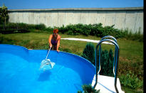 <p>Una persona limpia su piscina, que se sitúa justamente al lado del lugar por el que discurre el muro. (Photo by Thierlein/ullstein bild via Getty Images)</p> 