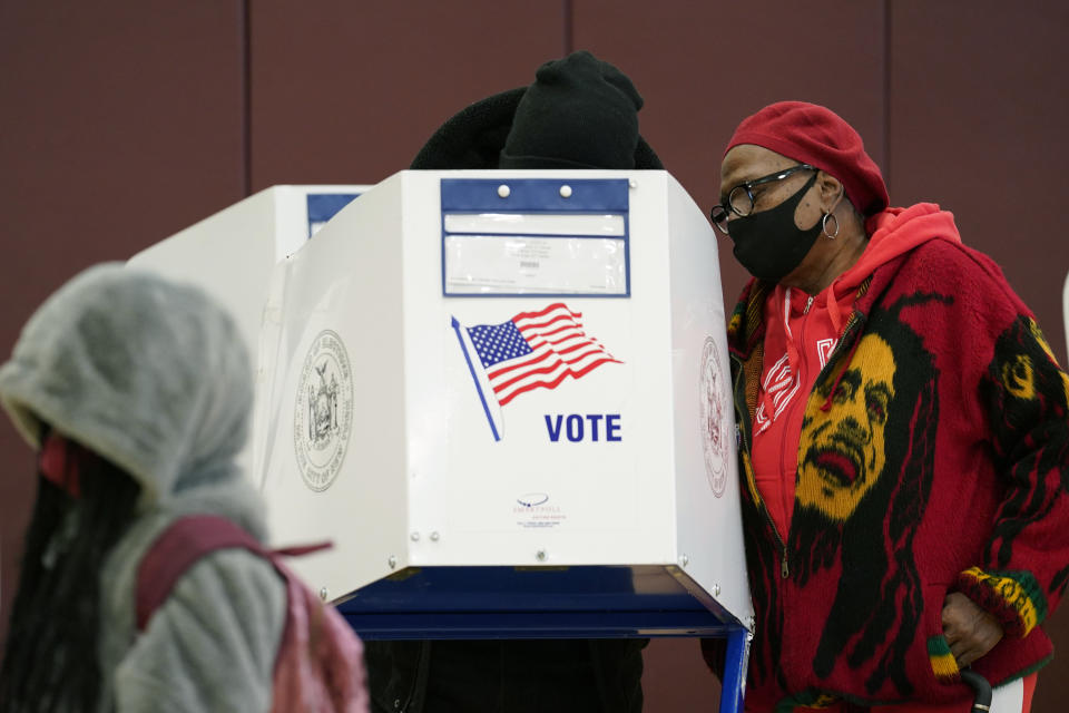 A woman helps a man cast his ballot in person on the last day of early voting, Sunday, Nov. 1, 2020, at P.S. 175 in the Harlem neighborhood of New York. (AP Photo/Kathy Willens)