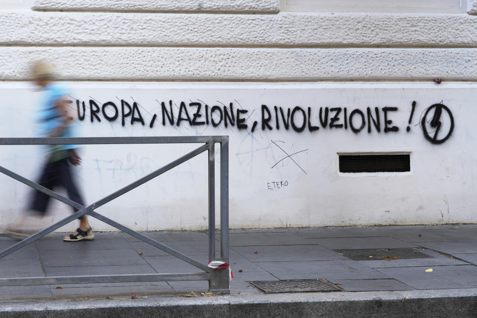 A woman walks past a mural by right wing students movement named "Blocco Studentesco" (Student Block) and reading : Europe, Nation, Revolution in downtown Rome, Sunday, Aug. 13 ,2023. When Giorgia Meloni was running to become Italy’s first far-right head of government since the demise of the country's fascist dictatorship, she steeped her campaign in ideological touchpoints like national sovereignty and “traditional families.” (AP Photo/Gregorio Borgia)