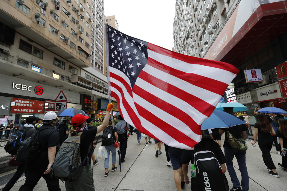 Protesters carry a U.S. flag as they march through the Mong Kok neighborhood during a demonstration in Hong Kong, Saturday, Aug. 3, 2019. Hong Kong protesters ignored police warnings and streamed past the designated endpoint for a rally Saturday in the latest of a series of demonstrations targeting the government of the semi-autonomous Chinese territory. (AP Photo/Vincent Thian)