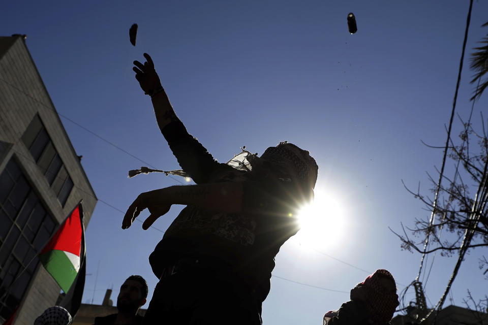 Protesters throw stone during a protest is held against the proposed peace deal for the Middle East by President Donald Trump, near the U.S. embassy in Aukar, east of Beirut, Lebanon, Sunday, Feb. 2, 2020. Hundreds of Lebanese and Palestinians demonstrated Sunday near the U.S. embassy in Lebanon in rejection to a White House plan for ending the Israeli-Palestinian conflict. (AP Photo/Hassan Ammar)