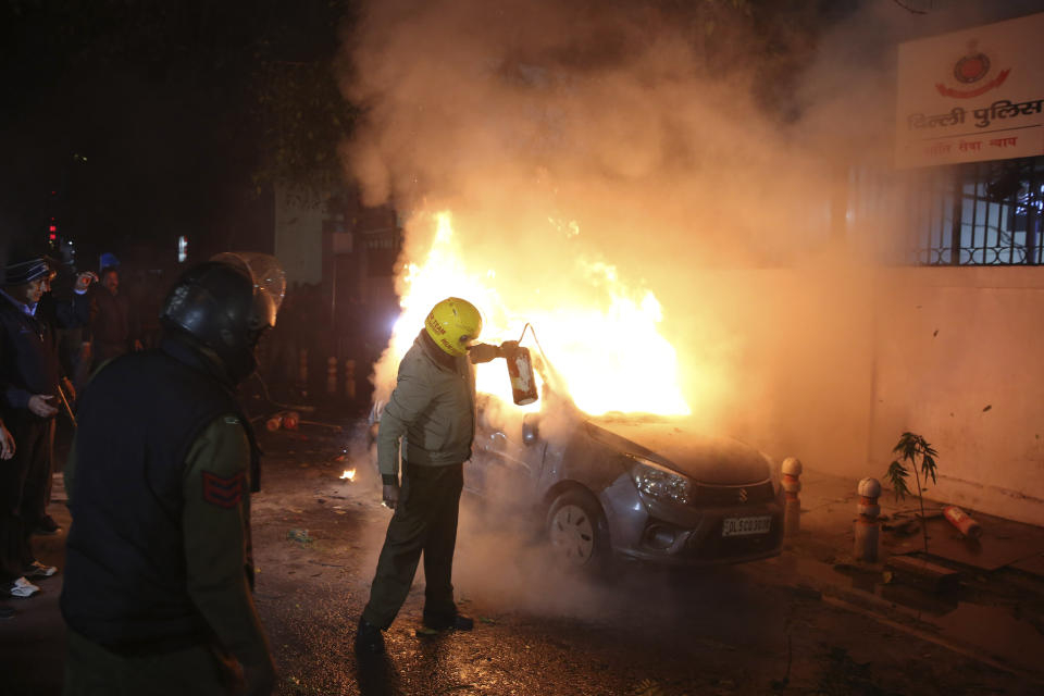 A security officer tries to put off a fire after after violence erupted Friday during a protest against the Citizenship Amendment Act in New Delhi, India, Friday, Dec. 20, 2019. Police banned public gatherings in parts of the Indian capital and other cities for a third day Friday and cut internet services to try to stop growing protests against a new citizenship law that have left 11 people dead and more than 4,000 others detained. (AP Photo)