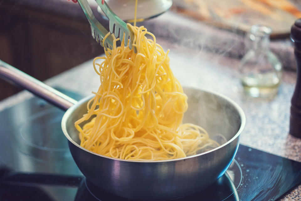 Grabbing cooked spaghetti with tongs.