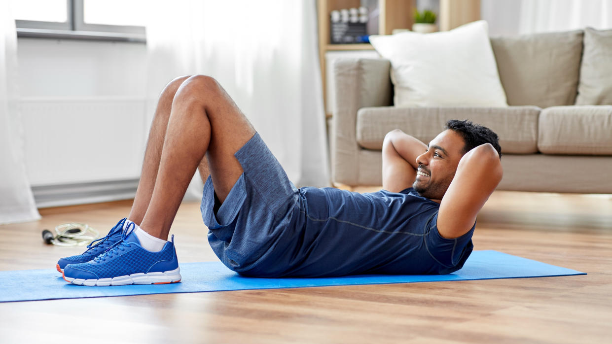  Man performs crunch in his living room. 