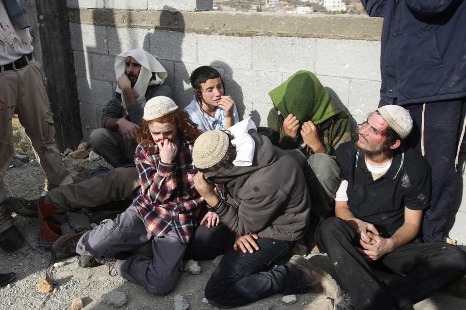 Jewish settlers sit together after being detained by Palestinian villagers near Nablus