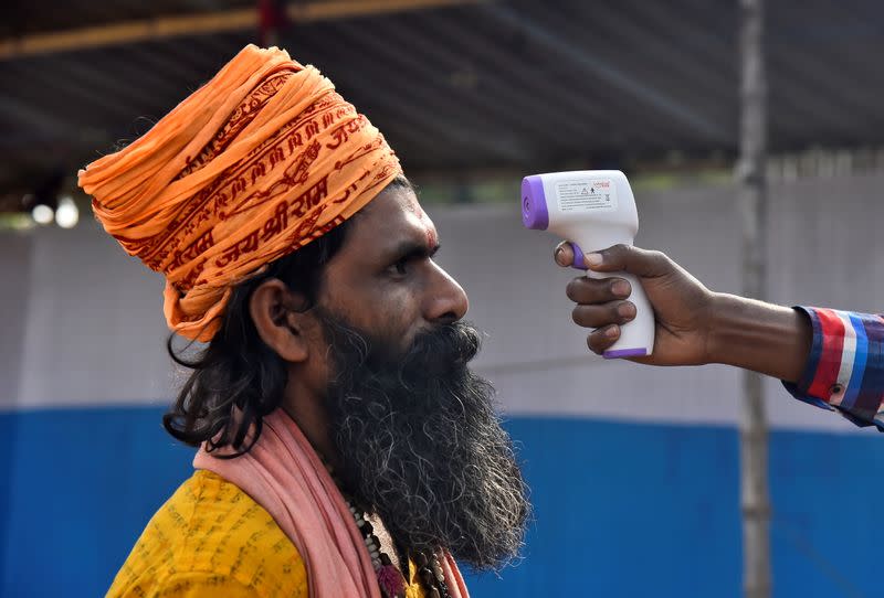 A Sadhu or a Hindu holy man gets his temperature measured at a base camp, in Kolkata