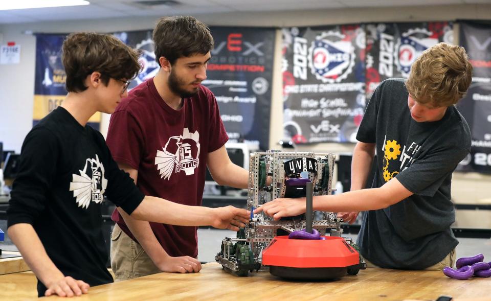 Firestone Robotics team members, from left, Eli Nisly, Andrew Stallsmith and William Forcey demonstrate how their robot works.