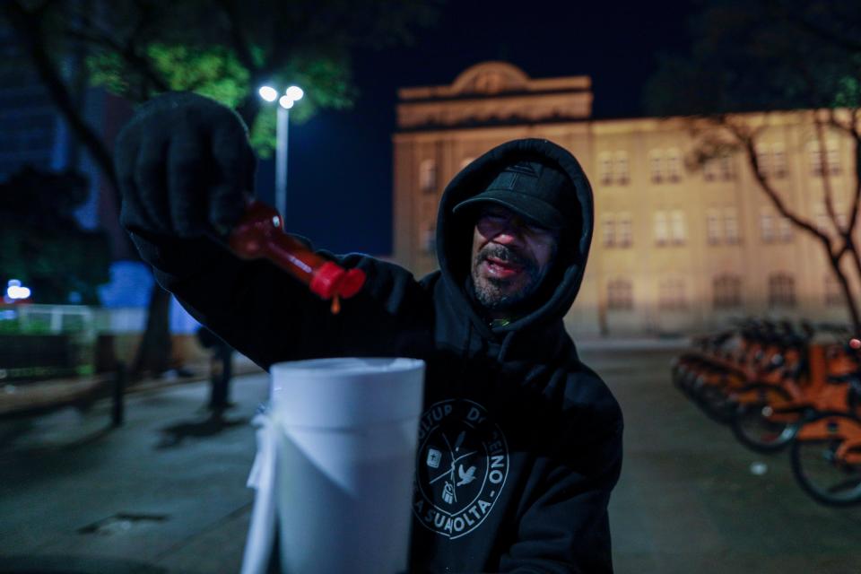Rodrigo, who says he has been homeless for 14 years, spices up a cup of soup with hot pepper sauce during a cold night in Sao Paulo, Brazil, Thursday, July 29, 2021. At least 43 cities in Brazil registered either snow or freezing rain late Wednesday. (AP Photo/Marcelo Chello) (AP Photo/Marcelo Chello) ORG XMIT: XEP123