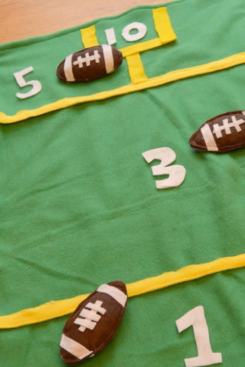 bean bag toss super bowl party game with a felt field on the floor and football shaped bean bags