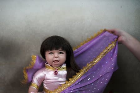 A devotee dresses up her "child angel" doll near Wat Bua Khwan temple in Nonthaburi, Thailand, January 26, 2016. REUTERS/Athit Perawongmetha