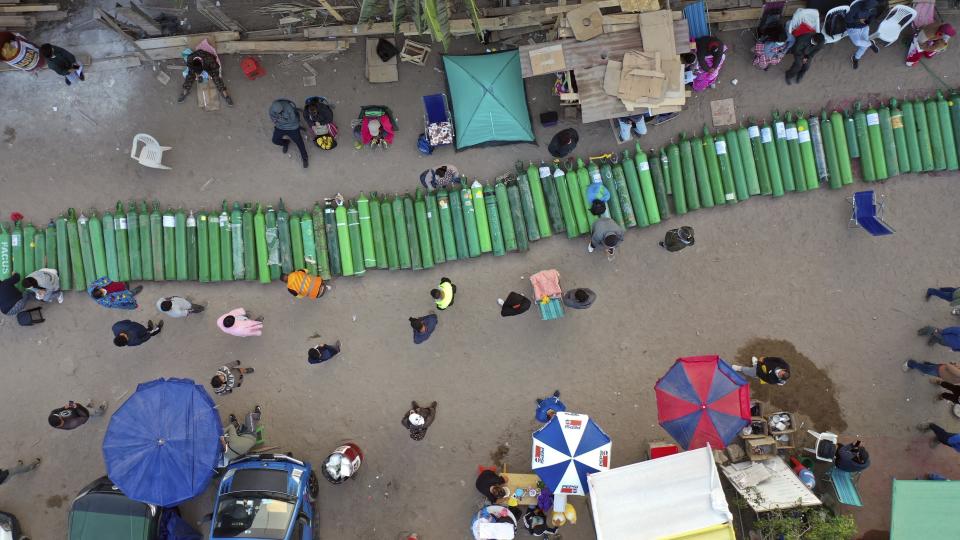 Dozens of empty oxygen cylinders lay across a dirt road, as people wait for a shop to open in order to refill their tanks in the Villa El Salvador neighborhood, as the lack of medical oxygen to treat COVID-19 patients continues in Lima, Peru, Tuesday, April 6, 2021. (AP Photo/Rodrigo Abd)