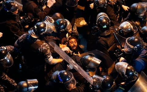Lebanon's riot police arrest an anti-government protester who was protesting outside police headquarters - Credit: AP