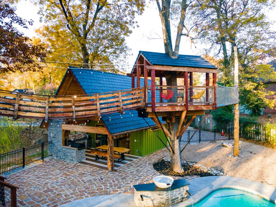 The treehouse is connected to a lookout patio via a swinging bridge.