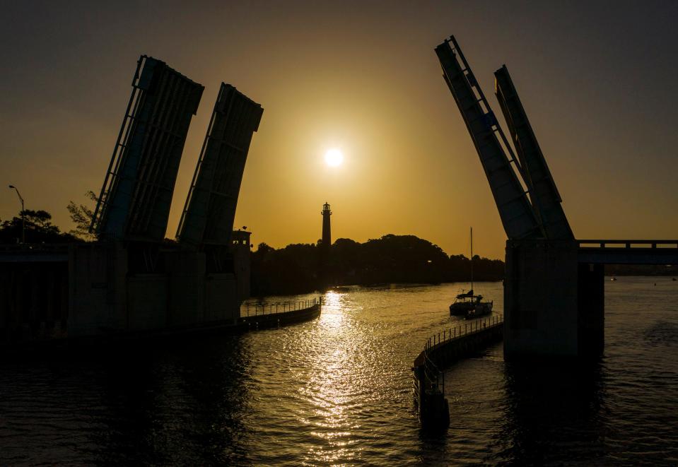 A boat passes under the U.S. 1 bridge as the sun rises in a hazy sky from Saharan dust in Jupiter, Fla., on July 1, 2020.