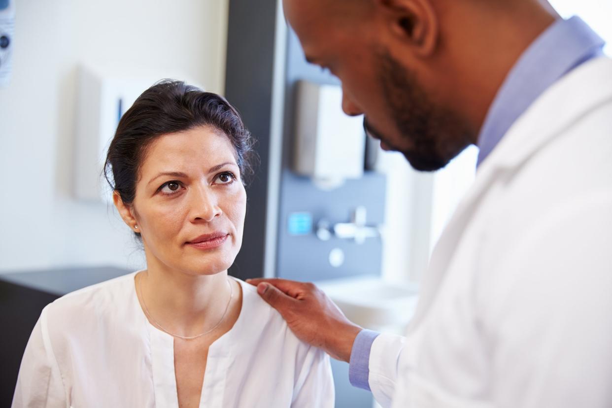 concerned female patient being reassured by doctor in hospital room