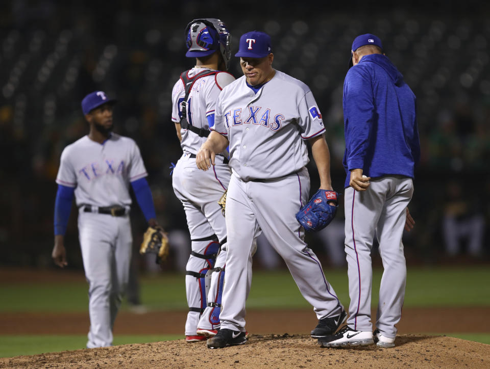 Texas Rangers' Bartolo Colon, center, walks off the mound after being relieved by manager Jeff Banister, right, in the sixth inning of a baseball game against the Oakland Athletics, Monday, Aug. 20, 2018, in Oakland, Calif. (AP Photo/Ben Margot)