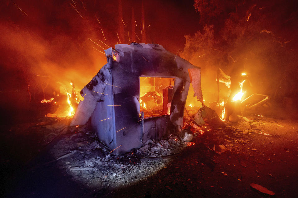 FILE - In this Aug. 19, 2020, file photo, flames from the LNU Lightning Complex fires consume a home in unincorporated Napa County, Calif. Two unusual weather phenomena combined to create some of the most destructive wildfires the West Coast states have seen in modern times. (AP Photo/Noah Berger, File)