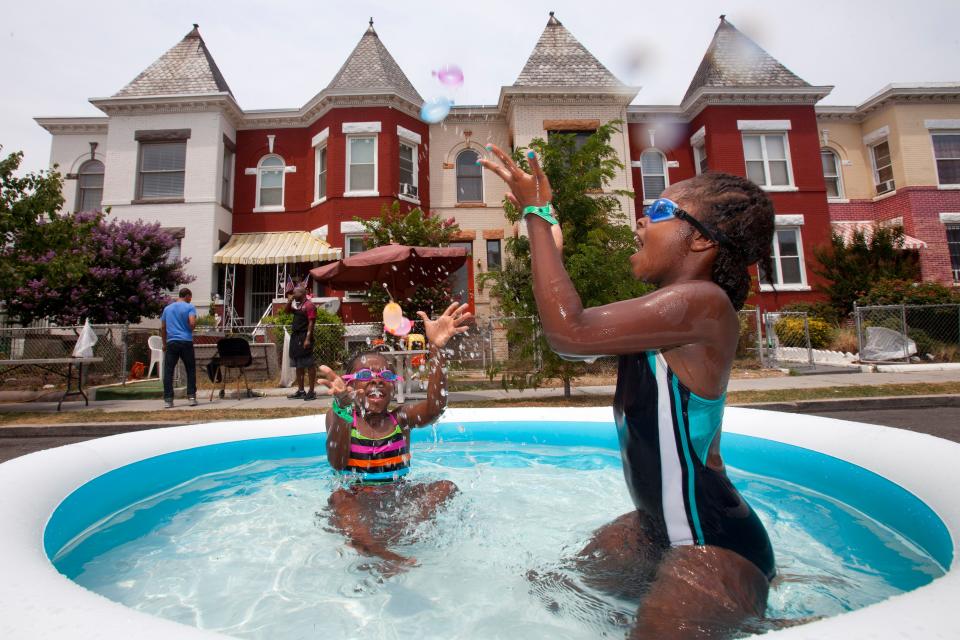 Nia Bailey, 8, of Washington, left, and Amari Swint, 8, of Philadelphia, throw water balloons while in an inflatable pool during a seventh annual block party on Newton Street in northwest Washington, during record heat with temperatures in the triple digits, Saturday, July 7, 2012.