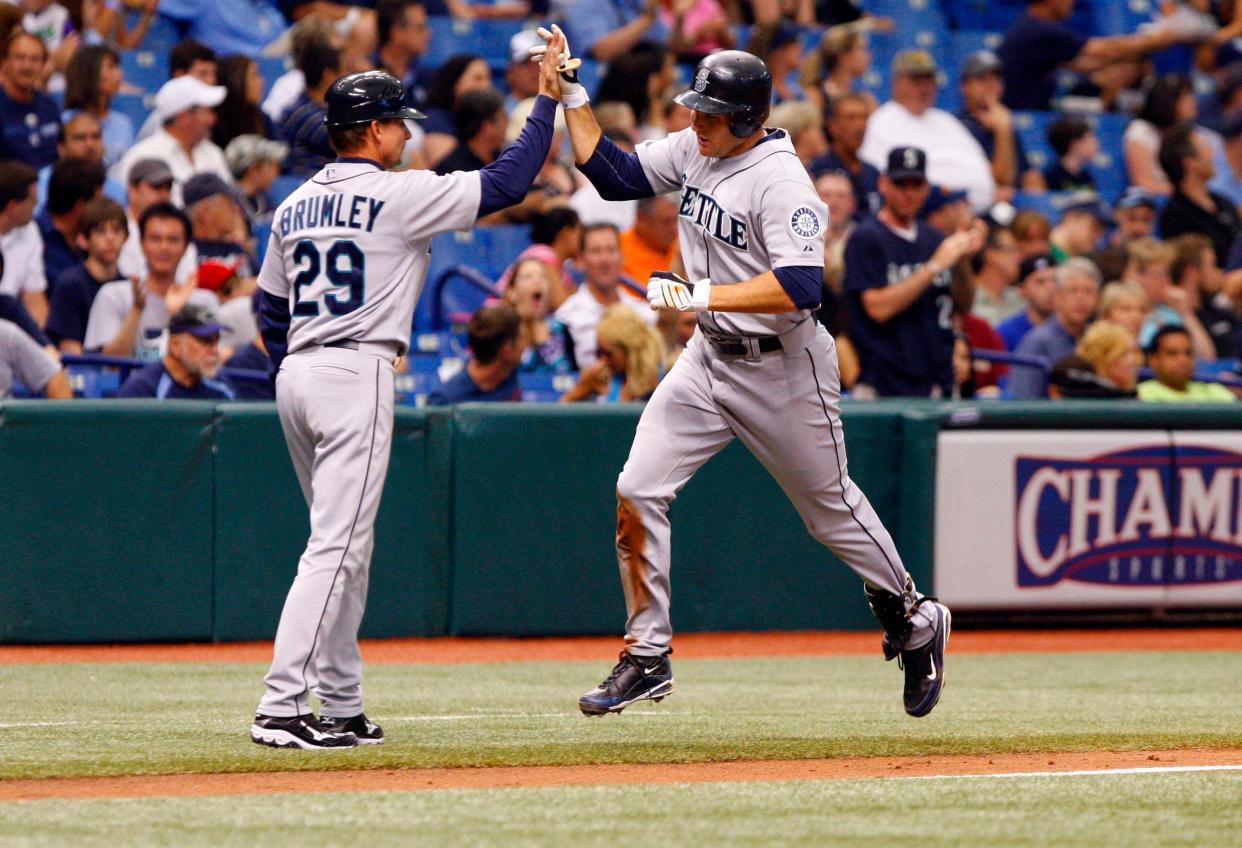 Seattle Mariners third base coach Mike Brumley high-fives Mike Sweeney after Sweeney's home run against the Tampa Bay Rays in a May 2010 game at Tropicana Field. Brumley, 61, died this past weekend in a car accident; he was the shortstop for Texas' 1983 national championship team.