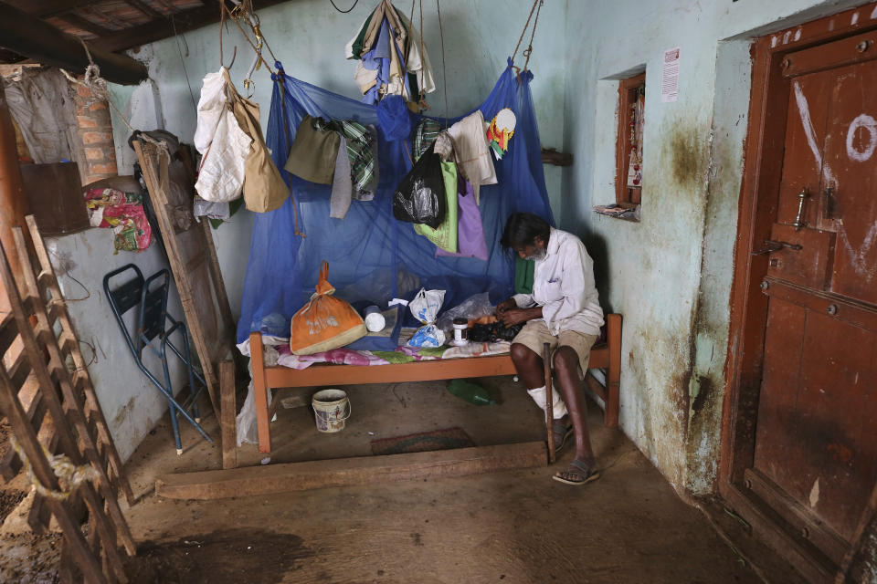 Kalmane Kamegowda, a 72-year-old shepherd, looks for some medicine in a plastic bag at his home after visiting a hillock where he has created 16 ponds, in Dasanadoddi village, 120 kilometers (75 miles) west of Bengaluru, India, Wednesday, Nov. 25, 2020. Kamegowda, who never attended school, says he's spent at least $14,000 from his and his son’s earnings, mainly through selling sheep he tended over the years, to dig a chain of 16 ponds on a picturesque hill near his village. (AP Photo/Aijaz Rahi)