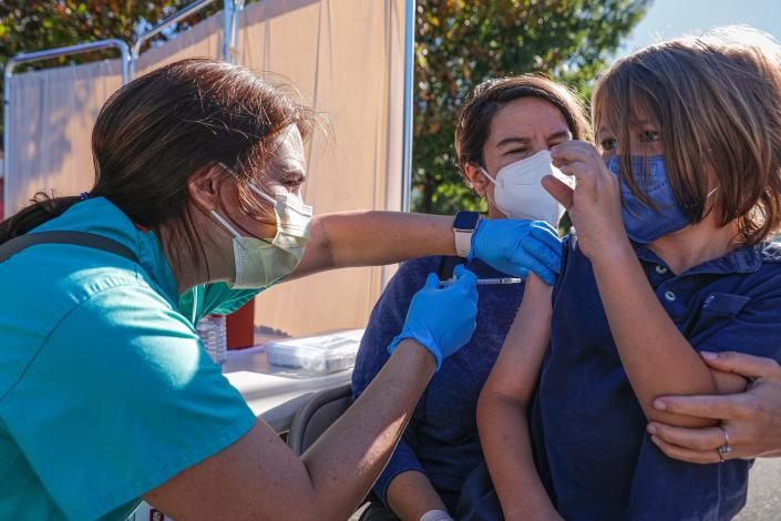 Doctor Allison Lopez, left, gives Oliver Howell, right, his first dose of a COVID-19 vaccine at a mobile clinic in Austin in November. Almost 70% of people ages 5 and older have been fully vaccinated in Travis County.