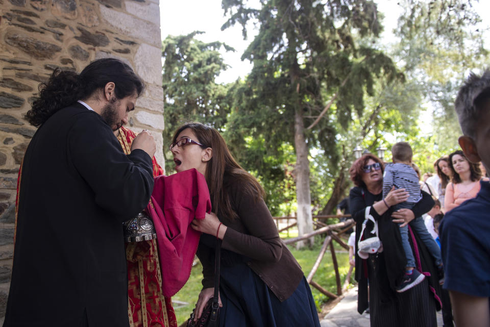 In this Sunday, May 24, 2020, photo, a Greek Orthodox priest uses a shared spoon to distribute Holy Communion during Sunday Mass in the northern city of Thessaloniki, Greece. Contrary to science, the Greek Orthodox Church and its followers insist it is impossible for disease, including the coronavirus, to be transmitted through Holy Communion. (AP Photo/Giannis Papanikos)