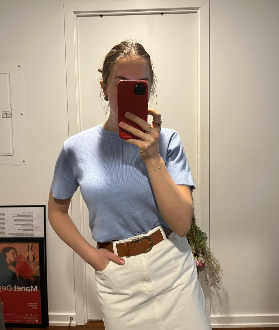 woman taking mirror selfie in blue t-shirt, brown belt and white denim skirt, H&M's Fine-Knit Top (Photo via author)