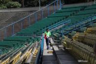 Foto del domingo de un vendedor caminando entre asientos vacíos en el estadio Universitario de Caracas