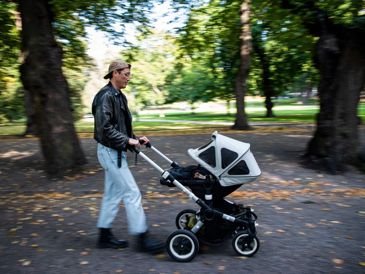 A man walks his baby in a baby stroller on Sept 24, 2020, in this file photo from Stockholm. New research has again suggested that it's childless men, not women, who are more likely to say they want to be parents some day. (Jonathan Nackstrand/AFP/Getty Images - image credit)