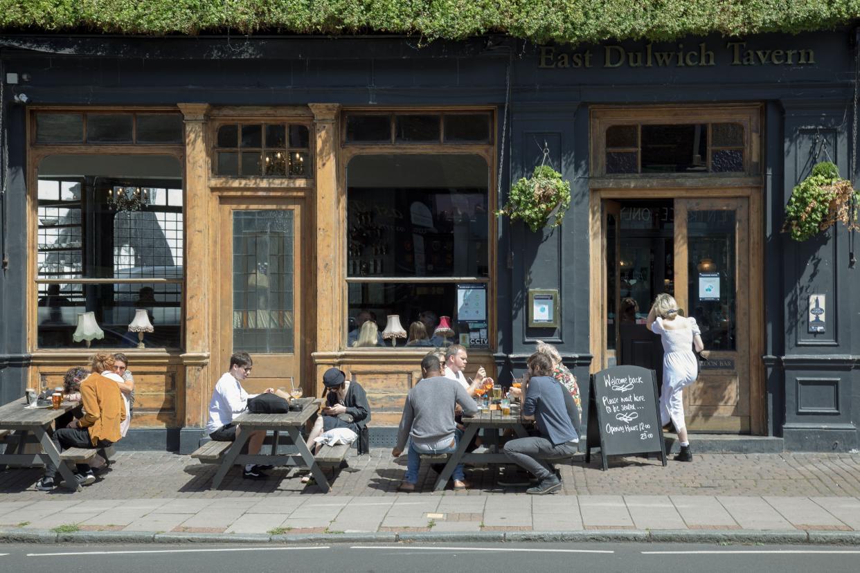 Customers drink outside the East Dulwich Tavern on July 5, 2020, in London, England. Pubs, restaurants and barber shops were among the businesses that could reopen across England on July 4 after being closed for over three months due to the coronavirus pandemic.