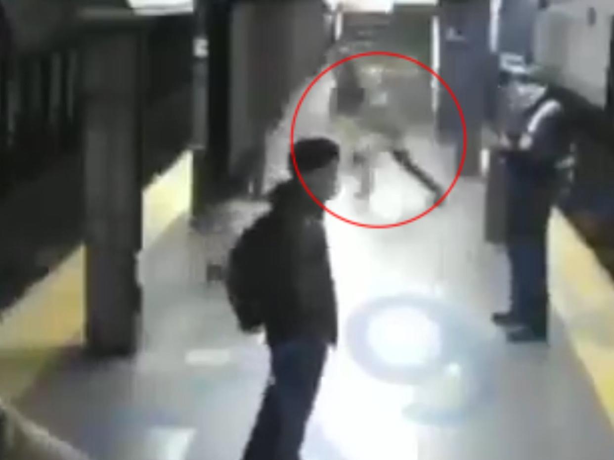 CCTV footage shows a man suddenly rushing forward to push a woman off a subway station platform onto the tracks as a train pulls into the station in New York (CCTV)