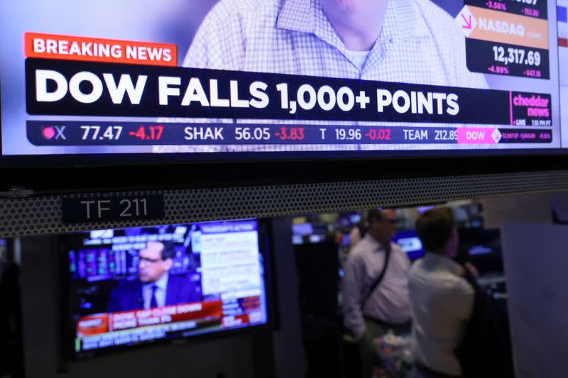 FILE PHOTO: Monitors display breaking news regarding the Dow Jones Industrial Average on the trading floor at the New York Stock Exchange in Manhattan, New York City