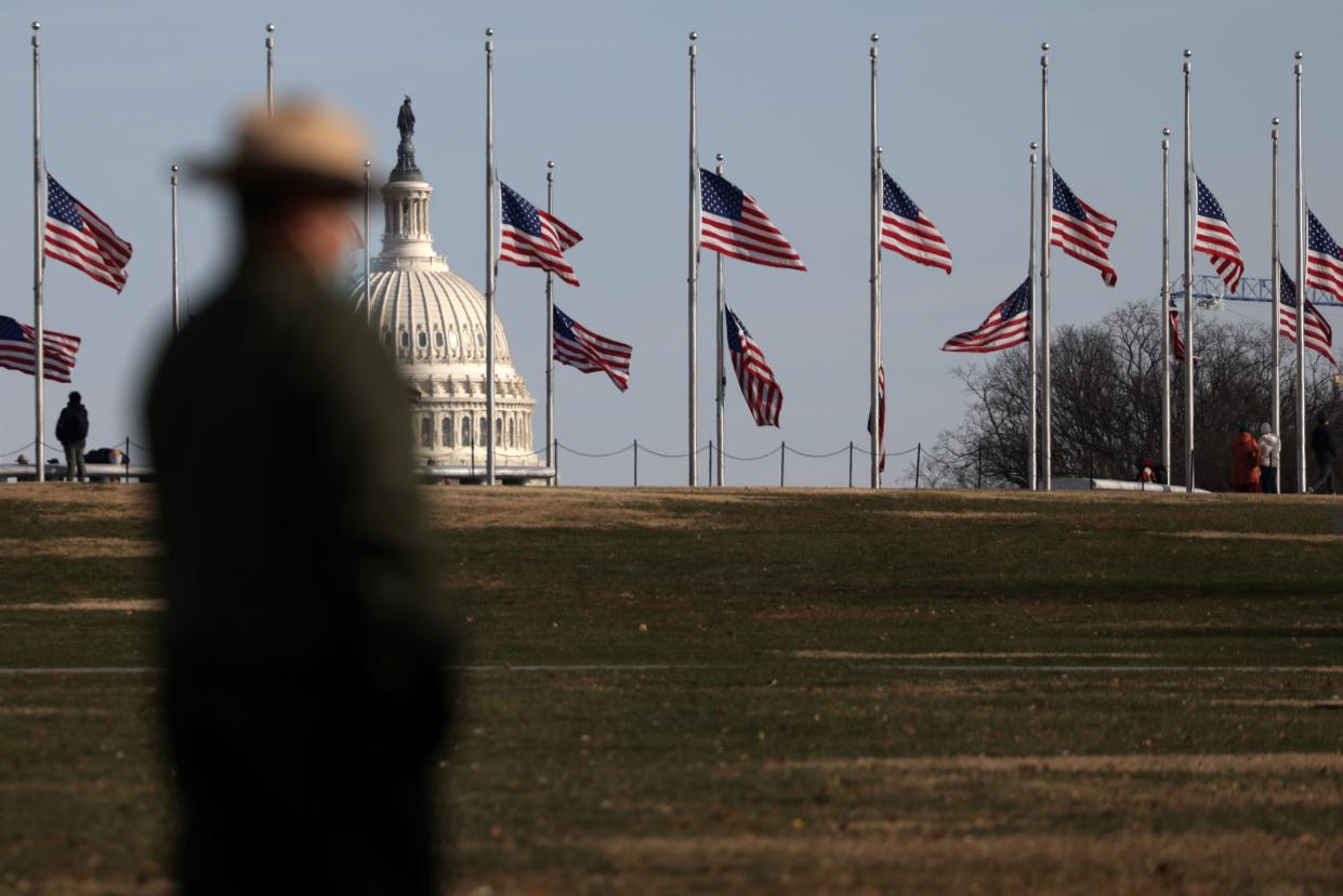 WASHINGTON, DC - DECEMBER 07: A U.S. National Park ranger looks at flags that are flying at half-staff on the grounds of the Washington Monument during a Pearl Harbor 80th Anniversary Commemoration at the World War II Memorial December 7, 2021 in Washington, DC.  (Photo by Alex Wong/Getty Images)