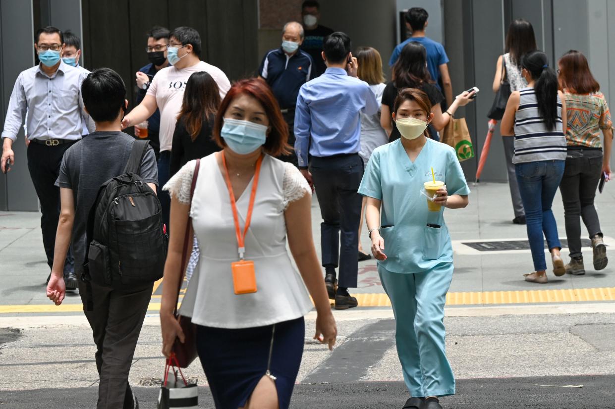 People walk out during lunch break at the Raffles Place financial business district in Singapore on September 14, 2021. (Photo by Roslan RAHMAN / AFP) (Photo by ROSLAN RAHMAN/AFP via Getty Images)