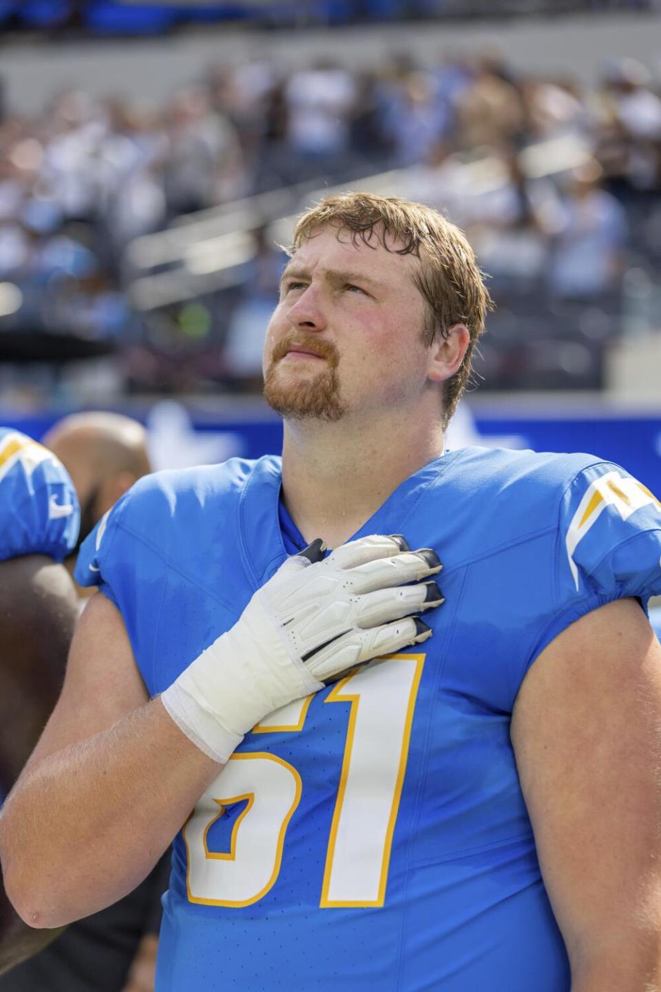 Chargers guard Karsen Barnhart (61) stands for the National Anthem with his hand on his heart.