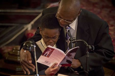 Half-brother of Akai Gurley, Malaki Palmer, is aided by his father Ken Palmer as he makes a reading during Gurley's funeral at the Brown Memorial Baptist Church in Brooklyn, New York December 6, 2014. REUTERS/Brendan McDermid