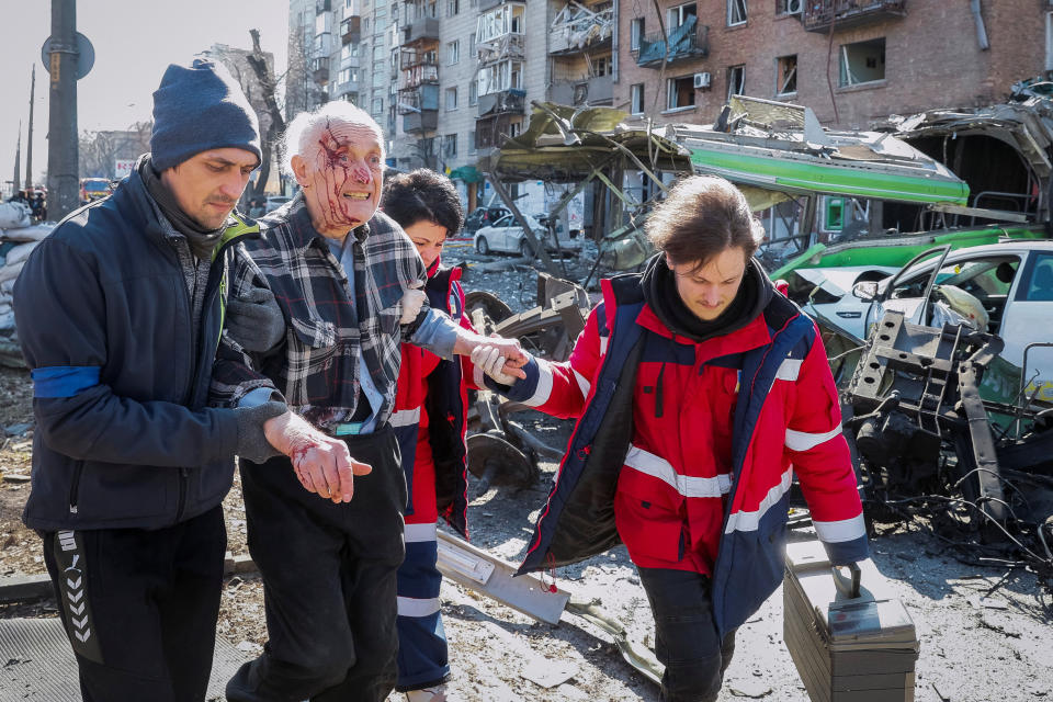 Image: People and medics help a wounded resident of a house destroyed by shelling in Kyiv (Gleb Garanich / Reuters)